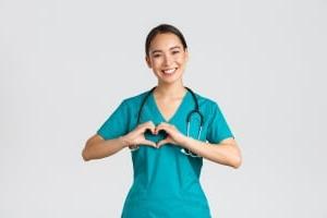 微笑的亚洲护士用她的手形成一个心脏